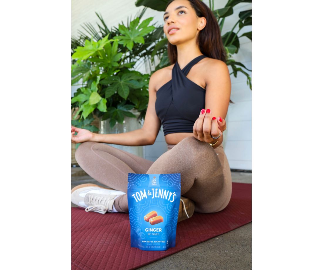 Image showing a young adult woman sitting in a yoga pose with a bag of ginger caramels nearby.