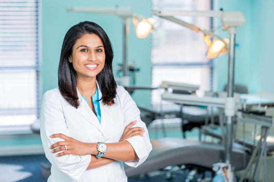A dentist, Dr. Jenny, in her white coat, standing with arms crossed in front of her clinic in the background, showing dental chairs and dental lights.