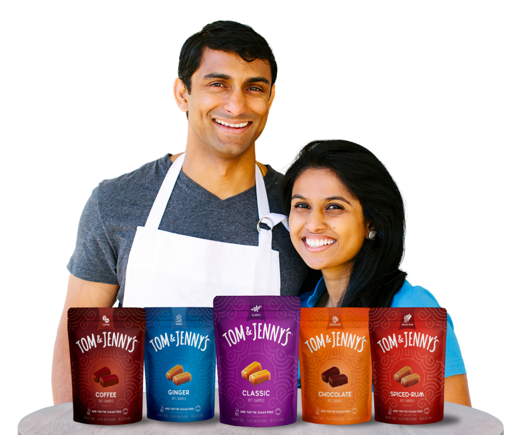 Tom and Jenny standing behind a table with all 5 flavors of Tom & Jenny's caramels