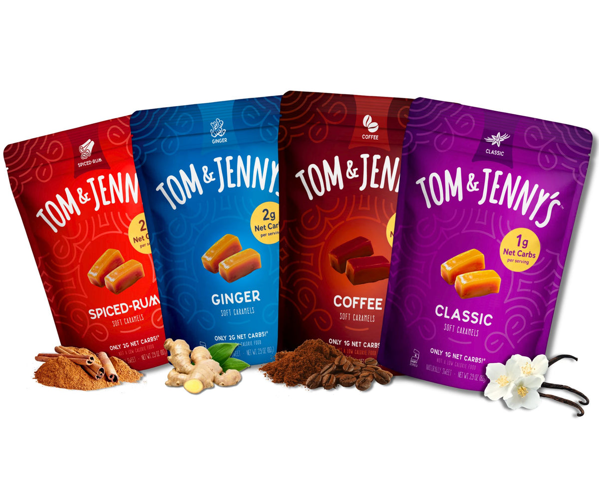 Four stand-up pouches of Tom & Jenny's caramel candies in different flavors (Spiced Rum, Ginger, Coffee, and Classic) arranged in a row with their respective flavor ingredients (cinnamon, ginger, coffee beans, vanilla beans) on a white background.